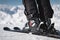 Close-up of the athlete`s skier`s foot in ski boots rises into the skis against the background of the snow-capped