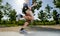 Close up athletic legs of young man running in city park with trees on summer training session practicing sport healthy lifestyle