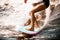 Close-up of athletic legs of young woman riding wave on surf style wakeboard