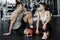 Close up of attractive pretty young fitness couple sitting together and having a break in the gym