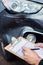 Close Up Of Auto Workshop Mechanic Inspecting Damage To Car And Filling In Repair Estimate