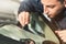 Close up Automobile glazier worker fixing and repair windscreen or windshield of a car in auto service station garage