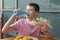 Close-up, baby boy sitting at a table drinking water from a bottle and eating fast food, a large Burger