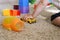 Close up of baby cup with children`s toys on the carpet. Elementary logic toys for the little ones. Pyramid, cubes, machine