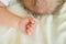 close up baby fist and crown with blond hair on the white blanket