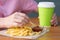 Close-up, baby girl`s hand holding French fries and dipping in ketchup, at the table