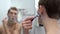 close-up of the back of the head of a man looking in the bathroom mirror, shaving his face after a shower, a thousand