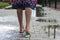 Close-up back view of slim white woman legs in comfortable casual rubber slippers and dress with floral design walking outdoors al