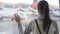 Close-up backside view of girl with backpack looking out window at airport on airplane background