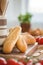 Close-up on baguette on wooden desk during breakfast with blurred tomatoes