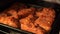 Close up of baked pork ribs on tray in oven. Seasoned meat with garlic fried in oven.