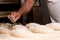 Close up of baker hand cutting and decorating fresh bread dough before baking it in the oven. traditional handmade work of