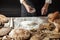 Close up of baker hands kneading dough and making bread with a rolling pin.