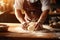 Close-up on baker\\\'s hands kneading a dough on a wooden table in bakery