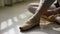 Close-up of ballerina`s feet. Ballerina preparing for training, and tying ribbon of pointe shoes sitting on floor in