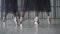 Close-up of ballet dancers legs in pointe shoes, tights and mesh skirt training in the choreography room on the wooden