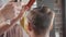 Close-up of barber splashes water on client`s hair before haircut.