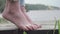 Close up of bare feet of girl standing on tips toes and trying to keep balance on wooden path