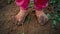 Close-up barefooted dirty feet of a child standing on a damp ground