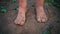 Close-up barefooted dirty feet of a child standing on a damp ground