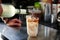 Close-up of barista pouring a liquid cocktail into a glass with drink while preparing a refreshing caffeinated iced drink