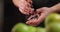 close-up barman hands with icebreaker crushes the ice for cocktails on the background of green apples.