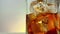 Close-up of barman pouring whiskey in the drinking glass with ice cubes on warm white background, time of relax drink with whisky