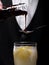 Close-up of a bartender pouring topping on a cocktail on a black background. Party drinks. Cocktail preparation concept.