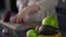 Close-up of a basket of fruits on the kitchen table. In the background, out of focus, an unrecognizable woman is cutting