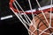 Close-up of a basketball falling through the net with arena lights in the background