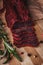 Close-up of basturma sliced into pieces. Dried meat with spices cut into slices. Dried horse meat on a wooden board with rosemary