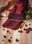 Close-up of basturma sliced into pieces. Dried meat with spices cut into slices. Dried horse meat on a wooden board with rosemary