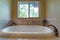 Close up of a bathtub and faucet adjacent to the sliding window of a bathroom