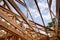 Close-up of beam built home under construction and blue sky with wooden truss, post and beam framework. Timber frame house, real