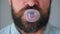 Close-up of a bearded man`s mouth chewing chewing gum. Man blowing out a bubble of bubble gum