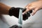 Close-up of beautician hands in black gloves filing client woman nails in shape using emery board.