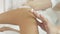 Close up beautician hands waxing elbow on girl hand by strips in beauty saloon.