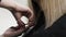 Close up of beautician`s hand with a comb cutting hair of woman