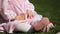 Close-up of the beautiful baby-girl seating on the green grass in the park.