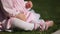 Close-up of the beautiful baby-girl seating on the green grass in the park.