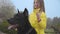 Close-up of beautiful big black doberman`s head with little cute girl standing behind. Pretty child in yellow coat