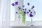 Close up of beautiful blue purple irises in vase, make-up mirror on window