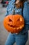 Close-up of beautiful bright orange pumpkin with carved smiling face in female hands