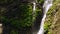 Close up of beautiful cascading waterfall with tropical vines, tilt down