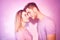 Close-up of beautiful couple kissing. Happy man and girl touching with their noses in pink background. Portrait of a loving