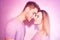 Close-up of beautiful couple kissing. Happy man and girl touching with their noses in pink background. Portrait of a loving