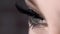 Close-up of beautiful female eye with long black lashes. Action. Extreme length of eyelashes, super black and swirled on