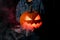 Close-up of beautiful glowing halloween pumpkin with smoking mouth and eyes on dark.