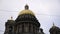 Close-up of the beautiful golden domes of Saint Isaac's Cathedral against the grey cloudy sky in Saint Petersburg