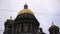 Close-up of the beautiful golden domes of Saint Isaac's Cathedral against the grey cloudy sky in Saint Petersburg